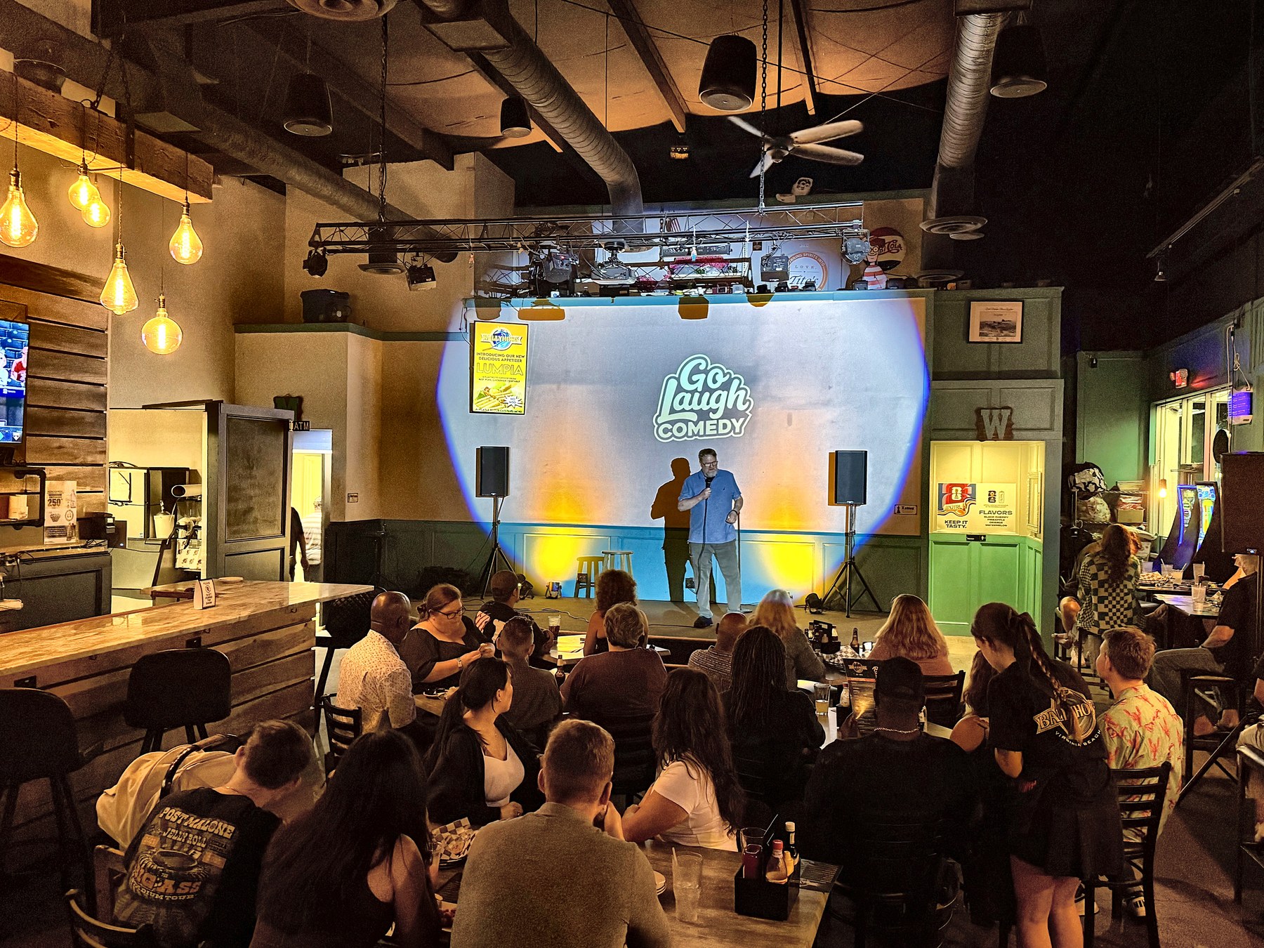 Full room watching a comedian perform at Ballyhoos