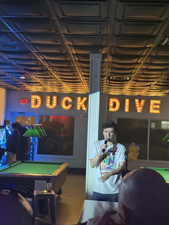 Comedian on the mic between the pool tables at Duck Dive