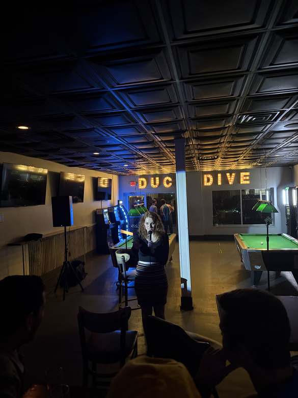 Comedian performing under the Duck Dive sign